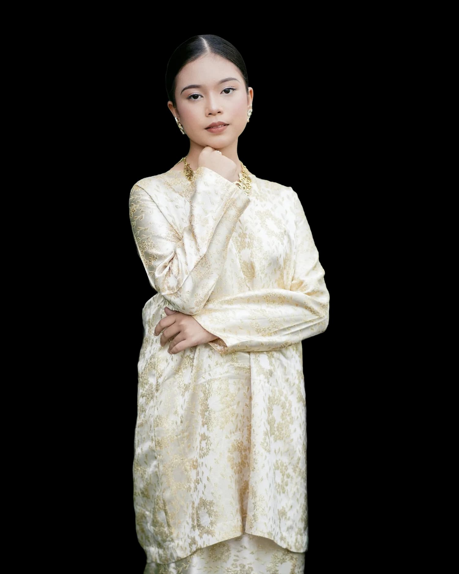 A model in a cream brocade baju kurung with gold thread