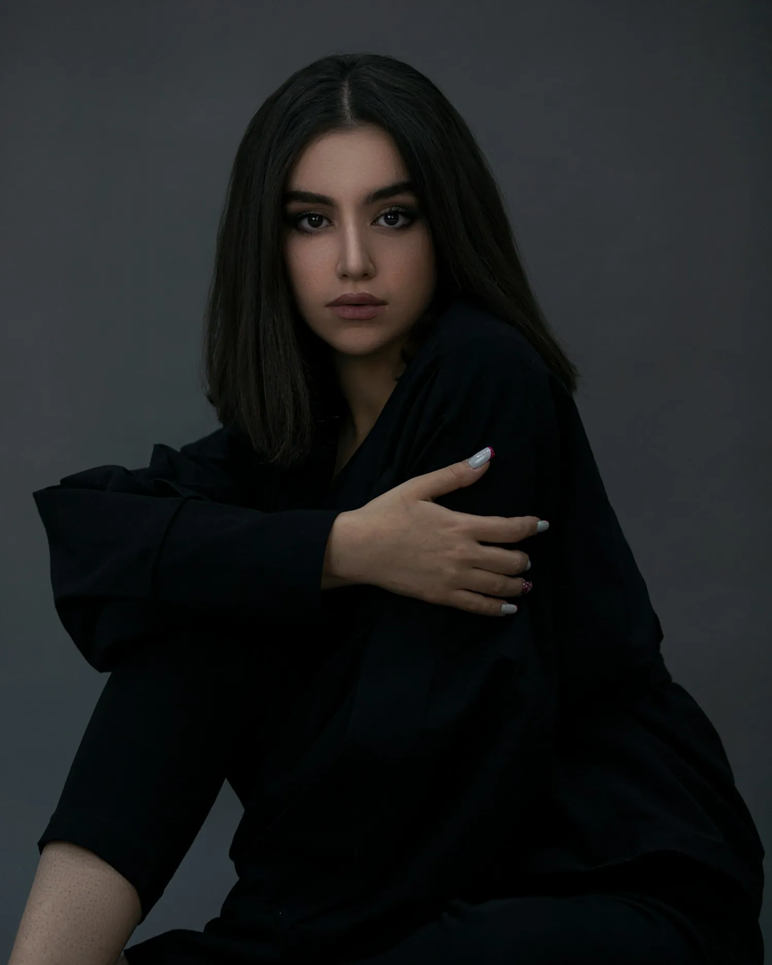 A model in black against a dark wall