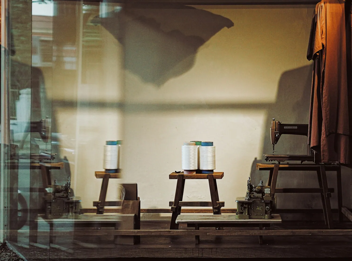 Spools of thread on wooden stools beside a sewing machine
