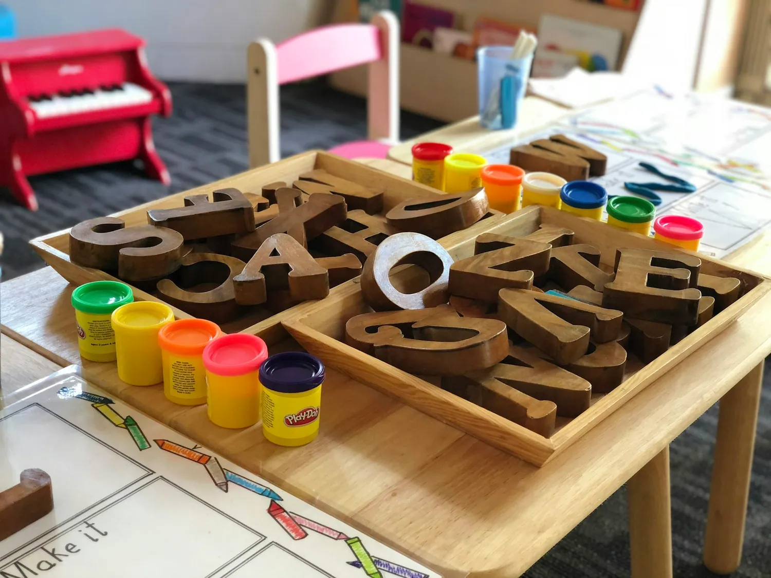 Wooden letters and tubs of modelling dough on a classroom tray